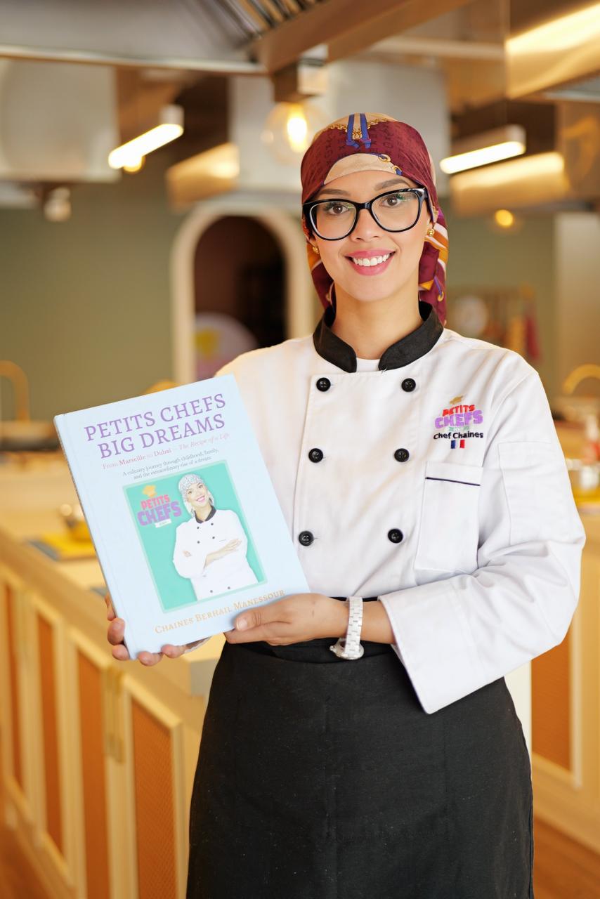Chef Chaines holding her book, Petits Chefs Big Dreams
